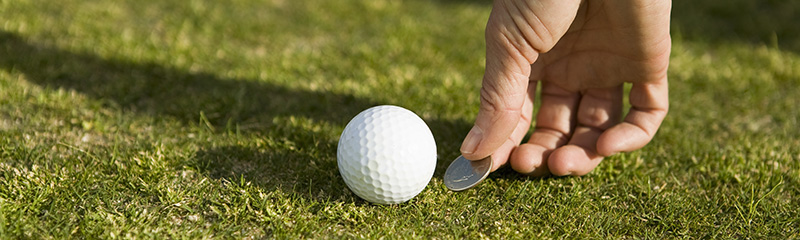 Detail of a golfer marking the ball's position with a coin.