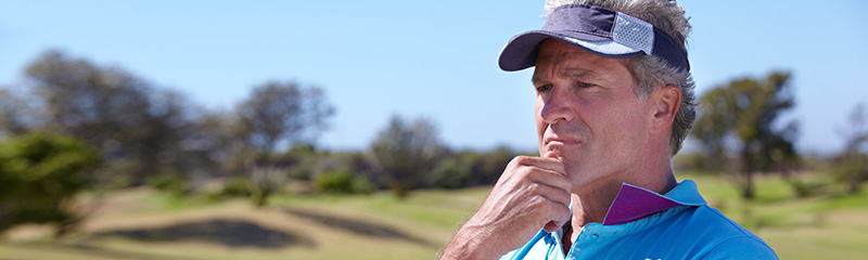 Golfer in polo and visor in deep thought.