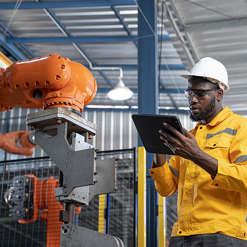 African American engineer working automatic robotic arm machine in factory. Male technician maintenance automatic robotic hand in smart factory, industrial and manufacturing concept.