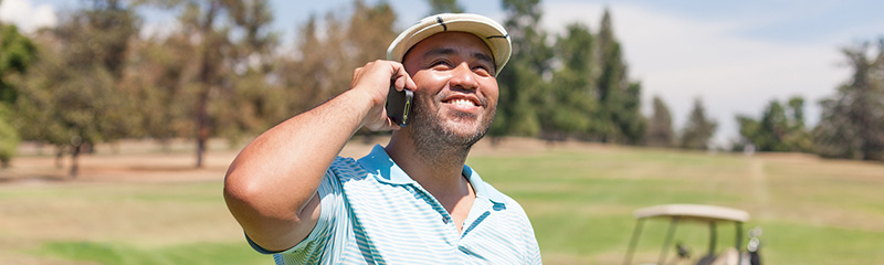 Golfer talking on cell phone at golf course.