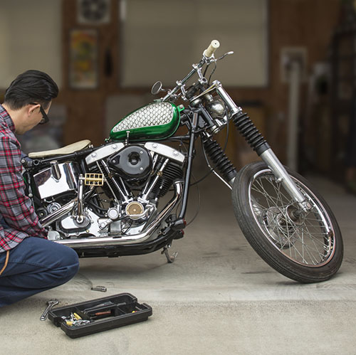 Man servicing motorcycle in garage.