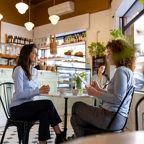 Women talking in a casual job interview at a cafe - small business concepts.