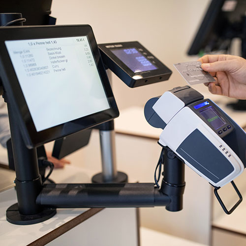 Hand of customer holding credit card for contactless payment at checkout in store.