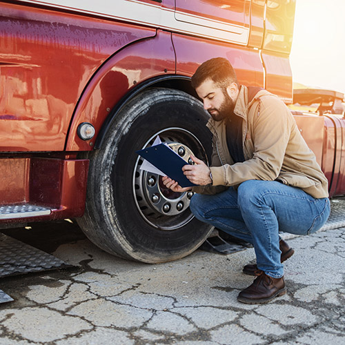 Man checking commercial vehicle parts before driving.