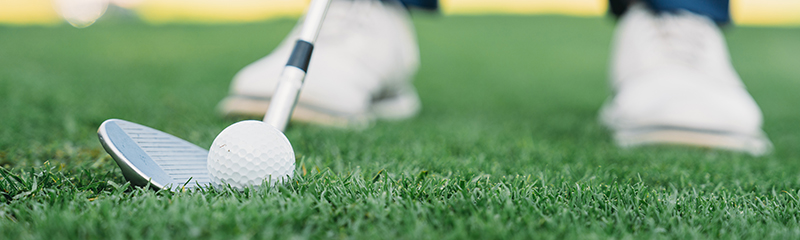 Detail of a golfer just before the swing. Focus on the golf club and ball.