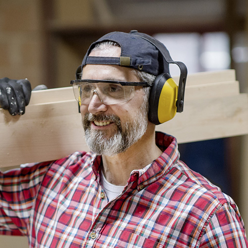 Mature carpenter wearing ear protection in the workshop.