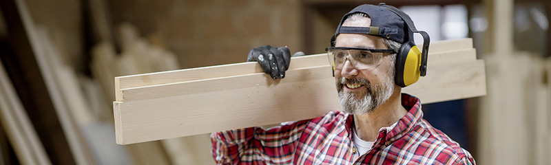 Mature carpenter wearing ear protection in the workshop.