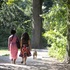 Two women in the park walking the dog, seen from behind.