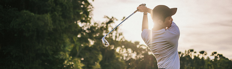 Golfer teeing off in golf course weekend morning.