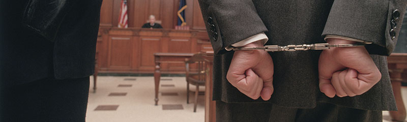 Businessman in handcuffs in courtroom.