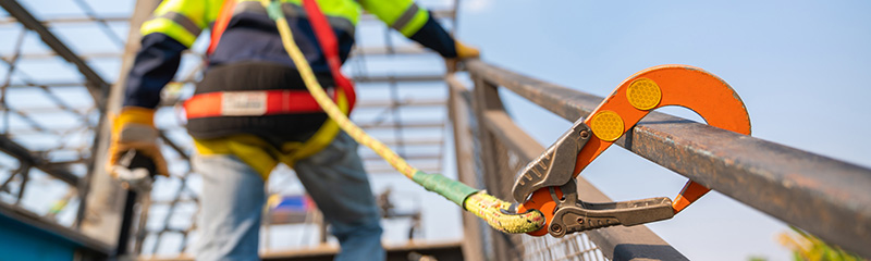 A construction worker working at height, Construction workers are working on steel roof trusses with Fall arrestor device for worker with hooks for safety body harness on the construction site.