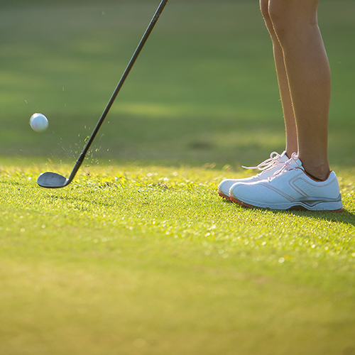 Close-up of a person's feet lined up to putt.