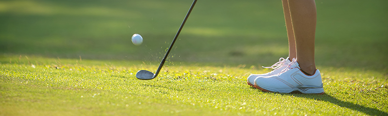 Close-up of a person's feet lined up to putt.