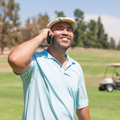 Golfer talking on cell phone at golf course.