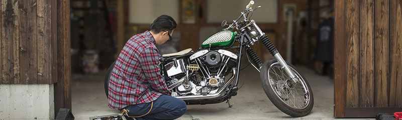 Man servicing motorcycle in garage.