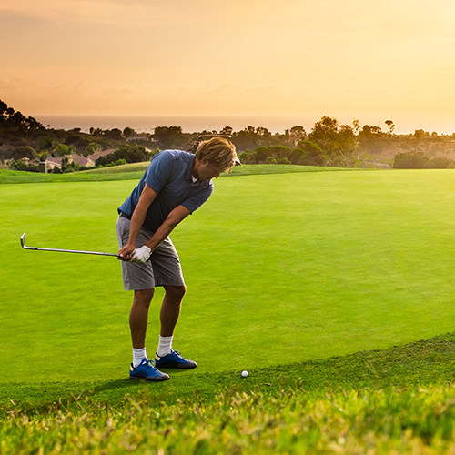 Male golfer about to swing at sunset.