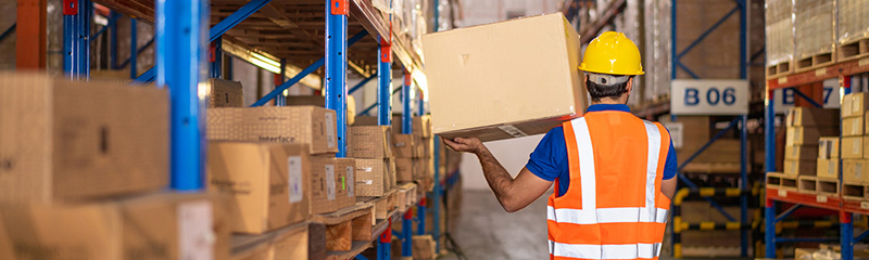 Man working at warehouse, carrying a box.