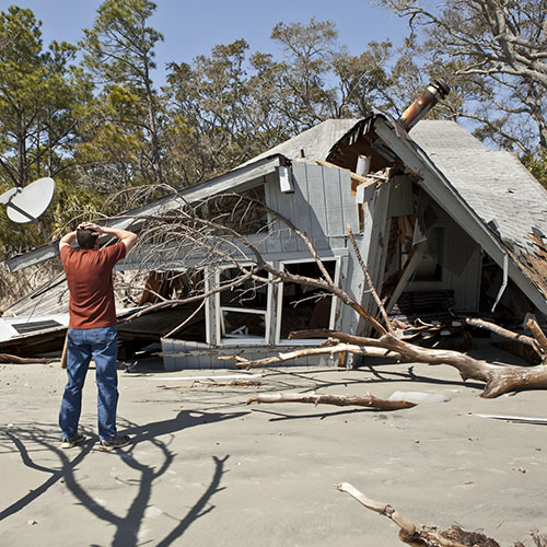 Man grieving over house destroyed in hurricane.