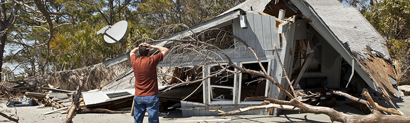 Man grieving over house destroyed in hurricane.