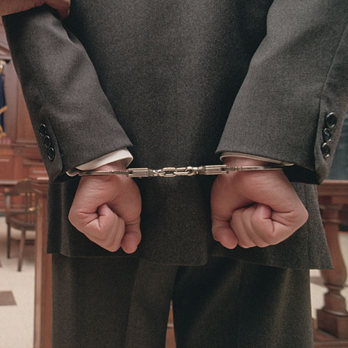 Businessman in handcuffs in courtroom.